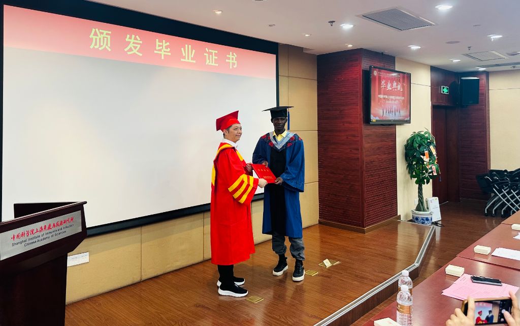 Handshake with a professor while holding the diploma on stage
